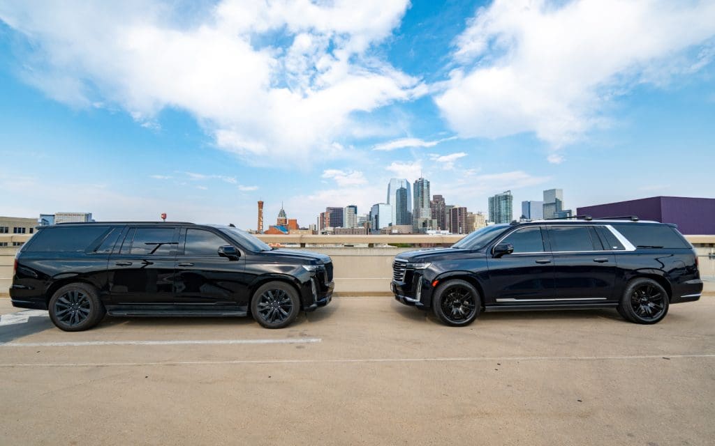 Black SUV staged for Empower Field transportation with downtown Denver behind it